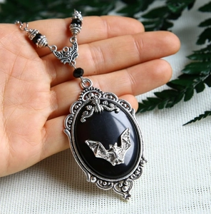 Close-up of vintage bat necklace with black oval gemstone and silver-tone beads