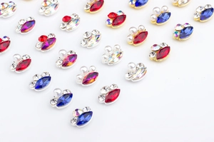 Macro detail of marquise nail gems with metal borders, pearls, and colorful rhinestones
