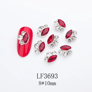 Macro detail of red marquise nail gems with metal edging and side accents