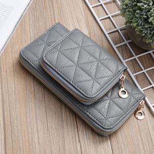 Grey quilted leather coin purse set with gold zippers on a rustic wooden desk background