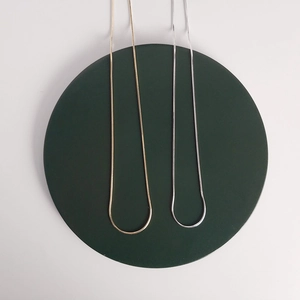 Macro shot of gold and silver octagonal snake bone chains on dark green display