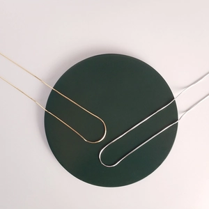 Close-up of minimalist 925 sterling silver and gold snake bone necklaces on tray