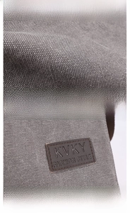 Close-up of durable gray canvas texture and premium brown leather brand logo patch