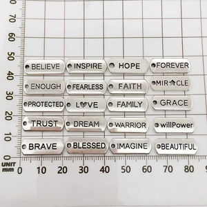 Close-up of rectangular alloy charms with inspirational words on a metric grid mat
