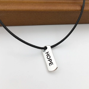 Detailed shot of silver HOPE engraved rectangular alloy pendant on black cord
