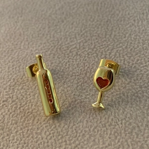 Macro detail of asymmetric wine bottle and glass studs with red zircon hearts