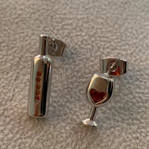 Macro view of asymmetric wine bottle and heart-shaped wine glass stud earrings