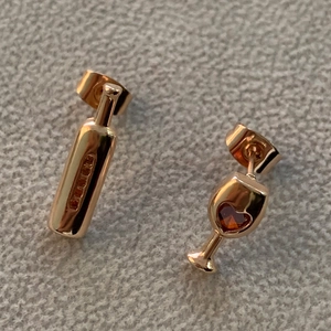 Detail of rose gold wine bottle and heart glass earrings with zircon stone