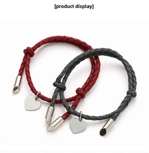 Close-up of woven braided couple bracelets with silver heart pendants in red and dark grey