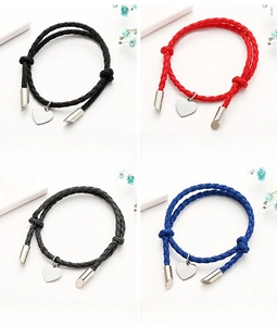 Detail view of woven couple bracelets in black, red, gray, and blue with heart charms