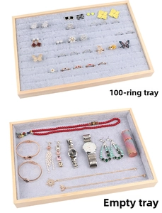 Close-up of wooden jewelry display tray with grey velvet lining for rings and necklaces