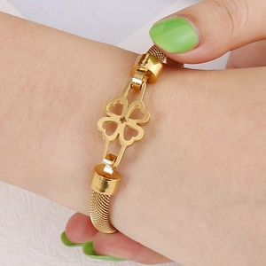 Gold stainless steel mesh bracelet with hollow clover charm worn on female wrist