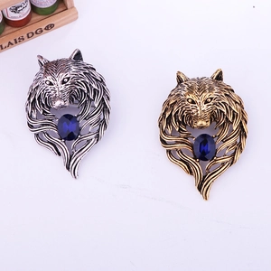 Detail view of retro wolf head brooch with realistic carving and a blue gemstone inlay