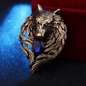 Macro detail of vintage wolf head brooch with bronze finish and a dark blue oval gemstone