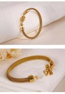 Close-up of golden mesh chain bracelet with geometric clasp on white fabric background