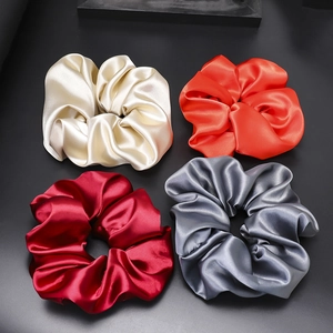 Glossy satin scrunchies set in cream, orange, burgundy, and dark grey silk fabric