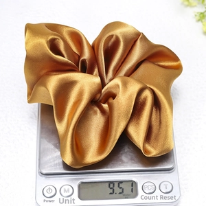 Detailed shot of a gold satin scrunchie weighing 9.5g on a digital scale