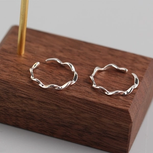 Pair of minimalist S925 sterling silver wavy twisted open rings on a walnut wood stand