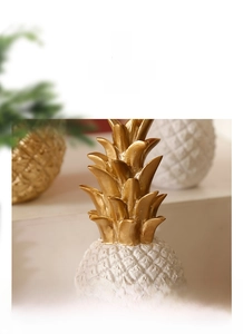 Detail shot of a resin pineapple ornament with golden leaves and textured white body