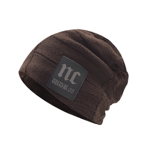 Detail of dark brown knit beanie with clear texture and gothic letter patch decoration