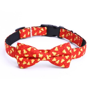 Detail of red dog collar with yellow bell pattern, bowtie and black safety buckle