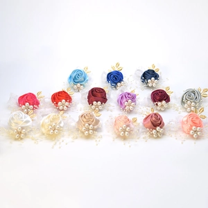 Macro shot showing diverse colors of fabric rose wrist corsages with faux pearls and gold leaves