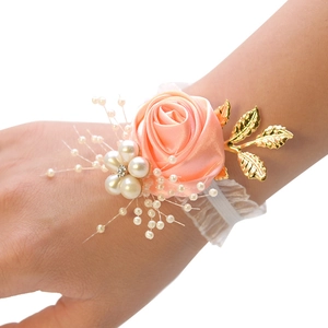 Detailed close-up of pink ribbon rose wrist corsage with pearls and golden leaves