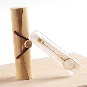 Detail of wooden storage tube with cord closure and golden metal lotus flower tool