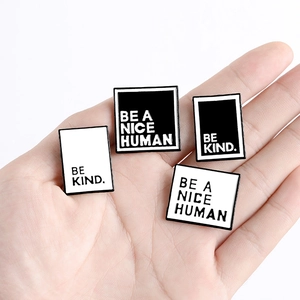 Broches en émail noir et blanc minimalistes avec texte Be A Nice Human tenues à la main