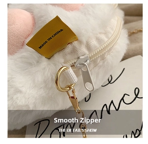 Detail showing the white plush fabric, smooth nylon zipper and metal chain hook of the bag