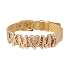 Detail of golden mesh bracelet with MOM pendant, star and bow charms with rhinestones