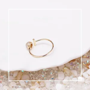 Close-up of gold-plated open ring with T-bar and crystal ball detail on ceramic tray