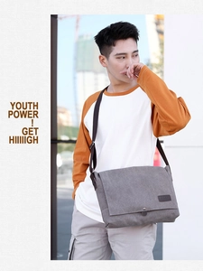 Outdoor model display of a grey canvas messenger bag with adjustable shoulder strap