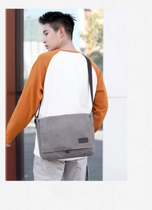 Close-up of a charcoal grey canvas messenger bag with adjustable strap and leather detail