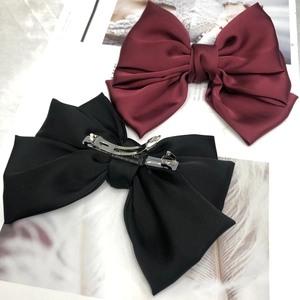 Detail of burgundy and black satin bow hair clips with silver metal spring fasteners