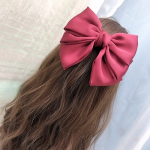 Burgundy satin bow hair clip with triple-layered ribbon shown on hair from behind
