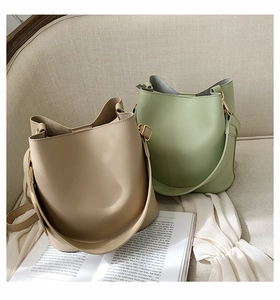 Detail view of stylish beige and sage green bucket bags on a soft sofa setting