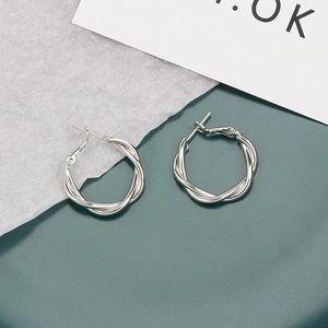 Close-up of silver-plated twisted hoop earrings with elegant woven texture design