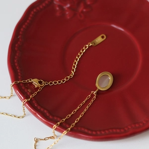 Detail showing the K18 hallmark on the gold chain clasp with a white cat eye pendant