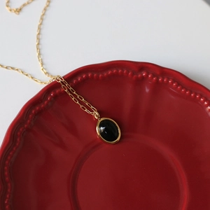 Detail of vintage oval black cat-eye stone pendant on 18K gold-plated necklace