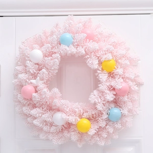 Pink Christmas wreath with pastel ornaments on white wooden door background