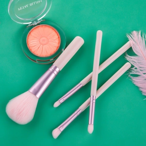 Rosa Make-up-Set mit Roségold-Pinseln und geprägtem Blumen-Rouge auf grünem Grund