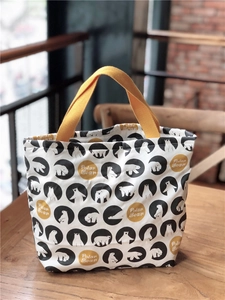Détail du sac à lunch en toile avec motifs d'ours polaires et poignées jaunes sur bois