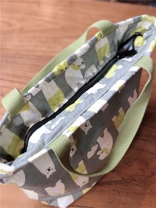 Détail de la fermeture éclair et des poignées du sac en toile à motif d'ours