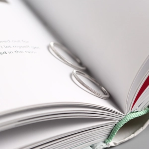 Close-up of minimalist silver rings with fine grainy texture on an open book background