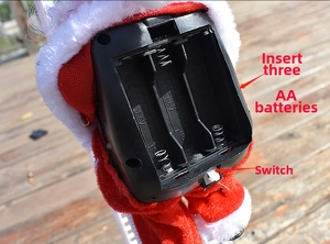 Detail of the battery compartment and power switch on the electric climbing Santa toy