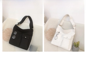 Detailweergave van grote canvas crossbodytassen in zwart en beige met handige voorvakken