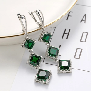 Macro shot of silver drop earrings with three green square stones in vertical design