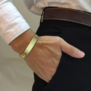 Polished gold stainless steel men bracelet with flat curved plate on male model wrist