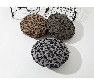Three leopard print wool berets in brown and grey colors displayed on a white surface